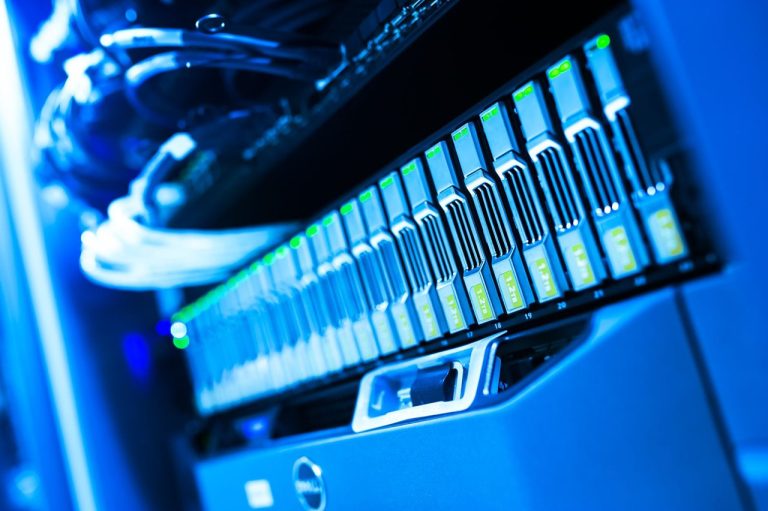 IonQ aposta em redes corporativas para transformar segurança quântica em negócio atual Rack de servidores iluminado em azul em um data center, representando a infraestrutura de redes corporativas e segurança digital
